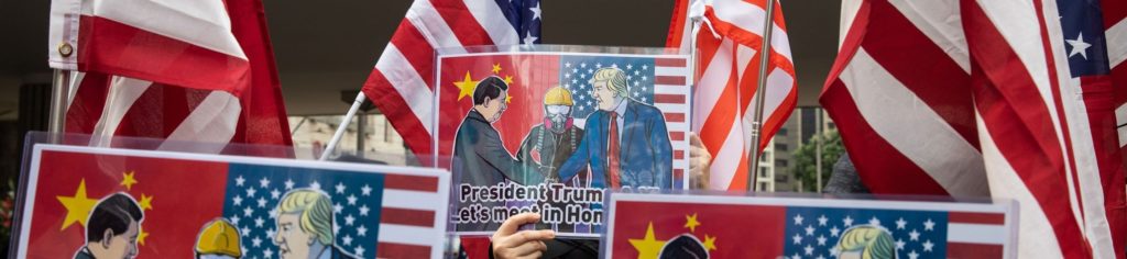 Demonstrators hold American flags and placards depicting China’s president Xi Jinping, and U.S. 